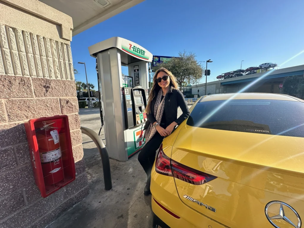 Fernanda Batista (Orlando Diferente) ao lado de carro alugado em posto de gasolina