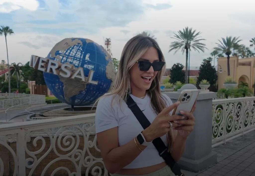 Fernanda Batista em frente ao globo da Universal, mexendo no celular