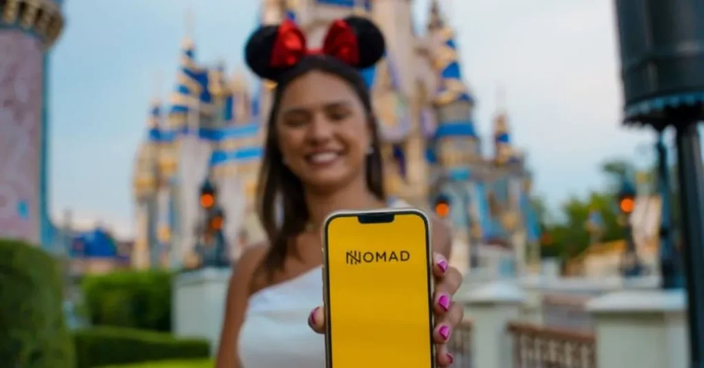 Fernanda Batista (Orlando Diferente) em frente ao castelo da Disney segurando celular no aplicativo da Nomad